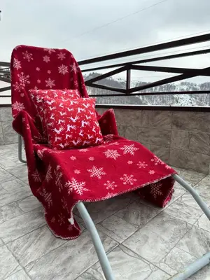 a red chair with a red blanket on it at Apartment Mountain View Haven in Kopaonik