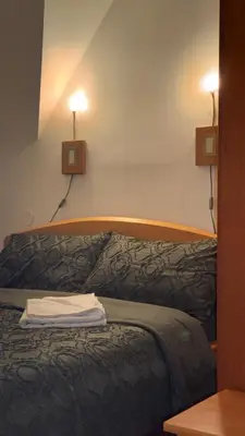 a bed in a room with two lights on the wall at Apartmani Čardaci Kopaonik in Kopaonik