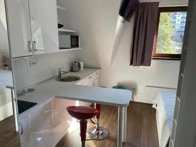 a small white kitchen with a counter and a stool at Apartments Sia-M3 in Kopaonik