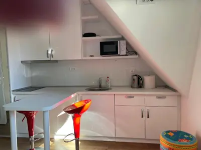 a white kitchen with a table and a microwave at Apartments Sia-M3 in Kopaonik