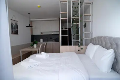 a bedroom with a white bed and a kitchen at Residence Hill A037 Apartment in Kopaonik