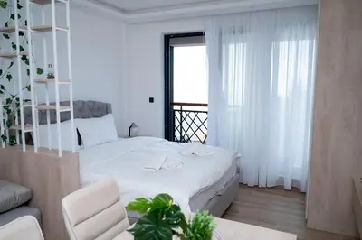 a white bedroom with a white bed and a chair at Residence Hill A037 Apartment in Kopaonik