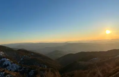 a view of a valley with the sun in the sky at Apartman Magdalena Kopaonik in Cajetina