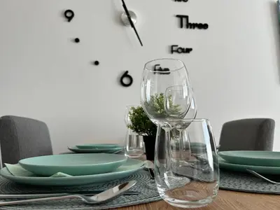 a table with glasses and plates and a clock on the wall at Apartman Magdalena Kopaonik in Cajetina