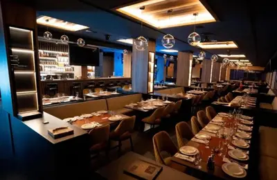 a restaurant with long tables and chairs and a bar at Apartman Magdalena Kopaonik in Cajetina