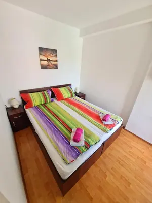 a bedroom with a bed with colorful sheets and pillows at Maja Vujković Apartman 5 in Soko Banja