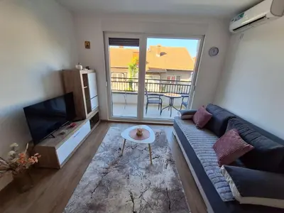 a living room with a couch and a tv and a balcony at Apartman Šara in Vrnjačka Banja