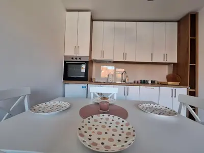 a kitchen with white cabinets and a table with two chairs at Apartman Šara in Vrnjačka Banja
