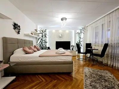 a bedroom with a bed and a living room at Deluxe Jade Apartmens in Niš