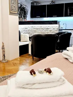 a room with a table with towels on a bed at Deluxe Jade Apartmens in Niš