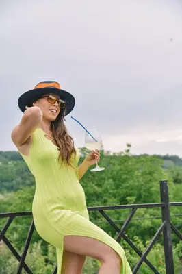 a woman in a yellow dress and hat holding a drink at Vila harmony in Trmčare