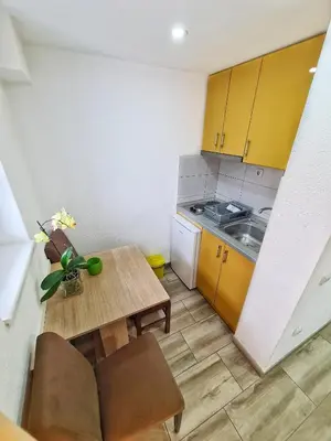 a small kitchen with a wooden table and yellow cabinets at Vila Aleksandra 2 Studio 2 in Soko Banja