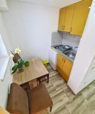a small kitchen with yellow cabinets and a wooden table at Vila Aleksandra 2 Studio 2 in Soko Banja