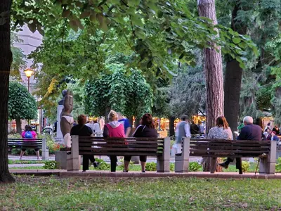 a group of people sitting on benches in a park at Vila Aleksandra 2 Studio 2 in Soko Banja