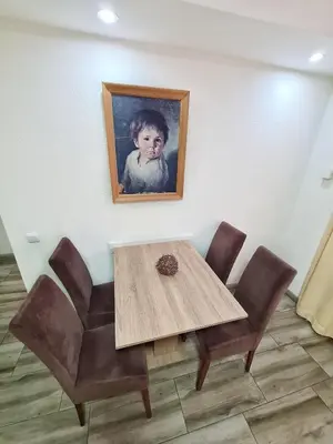 a table with chairs and a painting of a child at Vila Aleksandra 2 Apartman 1 in Soko Banja