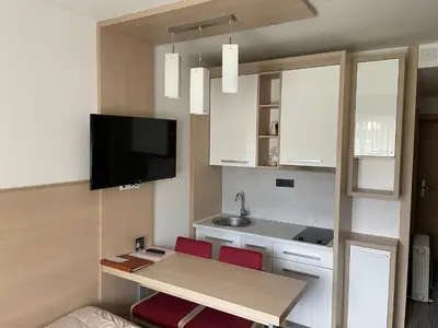 a small kitchen with a table and two red chairs at Konaci Angella apartman 126 in Kopaonik
