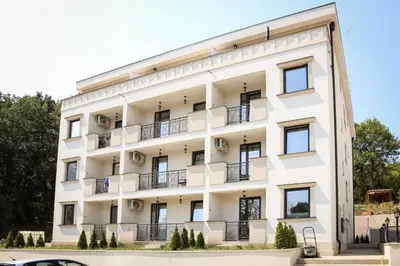a white building with balconies and trees at Apartman Schwarzkopf in Vrnjačka Banja