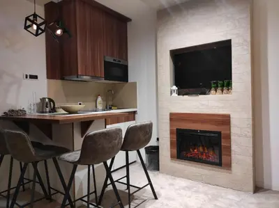 a kitchen with a bar with chairs and a fireplace at Apartmani Iva Kop Konaci in Kopaonik