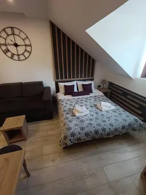 a bedroom with a bed and a couch and a clock at Kopaonik - Milmari resort S66 in Kopaonik