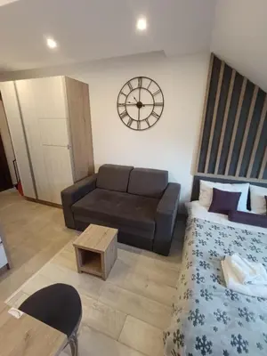 a living room with a couch and a clock on the wall at Kopaonik - Milmari resort S66 in Kopaonik
