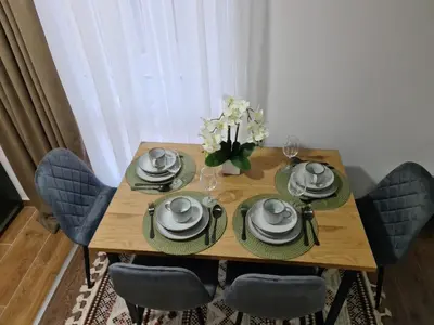 a wooden table with chairs and plates and a vase of flowers at Milanovic Apartman in Kopaonik