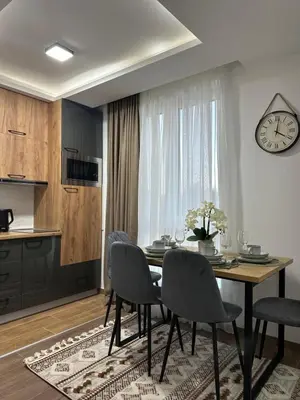 a dining room with a table and chairs and a clock at Milanovic Apartman in Kopaonik