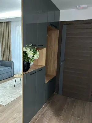 a room with a cabinet with a vase of flowers at Milanovic Apartman in Kopaonik