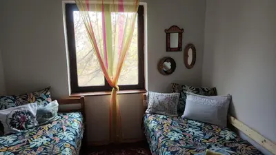a room with two beds and a window with curtains at Vila Seoska idila in Izvor