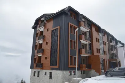 a tall building with a car parked in front of it at Vila Golija VM Apartment in Kopaonik