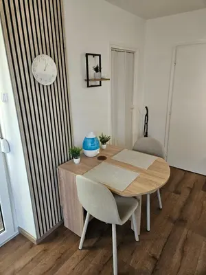 a dining room table with two chairs and a clock on the wall at Modern Apartment S22 in Niš