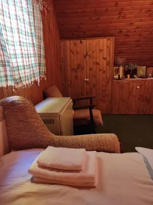 a room with a bed and a chair with towels on it at Drvenica Cabin in Kopaonik