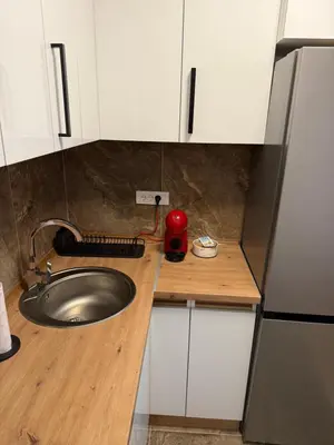 a kitchen counter with a sink and white cabinets at Smart Apartmani in Kruševac
