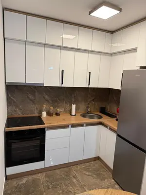 a kitchen with white cabinets and a sink and a refrigerator at Smart Apartmani in Kruševac