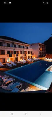 a swimming pool with lounge chairs in front of a building at Apartman Nina VB in Vrnjačka Banja
