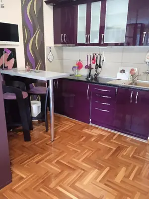 a kitchen with a table and a wooden floor at apartman Studenička in Vrnjačka Banja