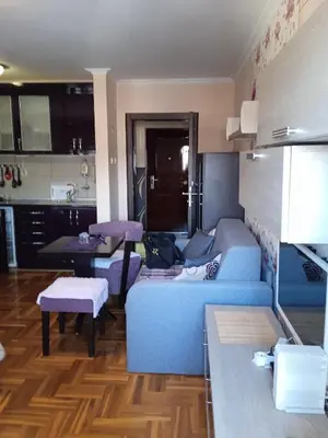 a living room with a blue couch and a kitchen at apartman Studenička in Vrnjačka Banja