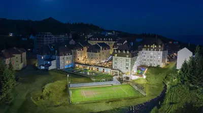 a large building with a tennis court in front of it at Kraljevi Cardaci, Kopaonik, Lux apartman 9C-71 in Kopaonik