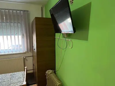 a flat screen tv hanging on a green wall at Slobo Velickovic in Čerkeška Mala