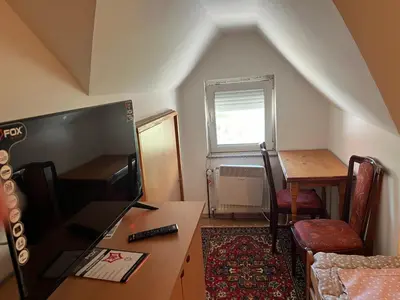 a small room with a desk and a table and a window at Slobo Velickovic in Čerkeška Mala