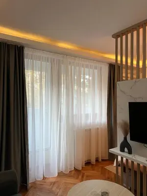 a living room with a large window with white curtains at NOMAD Studio in Niš