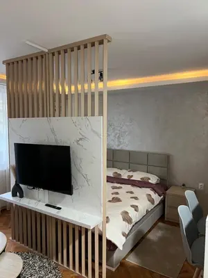 a bedroom with a bed and a flat screen tv at NOMAD Studio in Niš