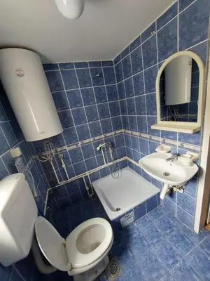 a blue tiled bathroom with a toilet and a sink at Sobe za izdavanje Nedeljković in Lukovo
