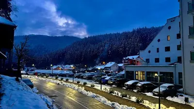 a snowy street with cars parked in a parking lot at Sobe za izdavanje Nedeljković in Lukovo
