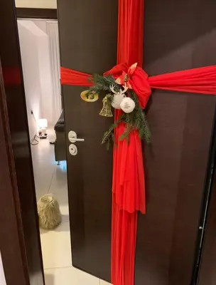 a door with a red ribbon and a christmas wreath at Sofija lux in Jagodina