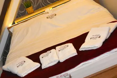 a bed with three white towels on top of it at SKI MONTIS apartmani - Kopaonik centar in Kopaonik
