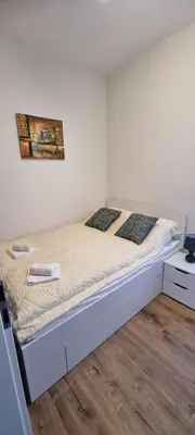 a bed in a white room with a bed frame at Apartman Magic house in Kruševac