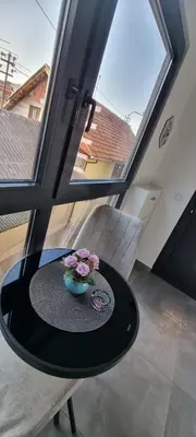 a table with flowers on it in front of a window at Apartman Magic house in Kruševac