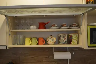 a shelf filled with different colored vases and cups at Apartman S32 Milmari in Raška