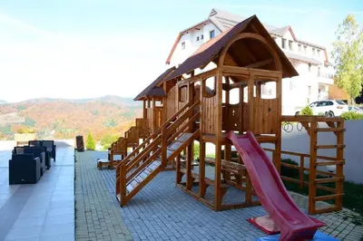 a group of wooden play structures with a slide at Apartman S32 Milmari in Raška