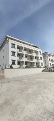 a large white apartment building with a parking lot at Apartman David in Vrnjačka Banja